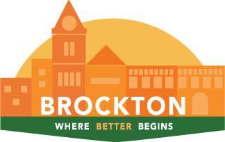 Logo featuring an orange cityscape with a rising sun behind it, symbolizing the city of Brockton. Below the buildings, the word “BROCKTON” is written in bold white capital letters. Underneath, a green banner reads the slogan: “Where Better Begins,” with the word “Better” highlighted in orange.